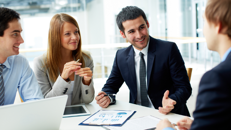A group of people in business attire discussing with an investment advisor